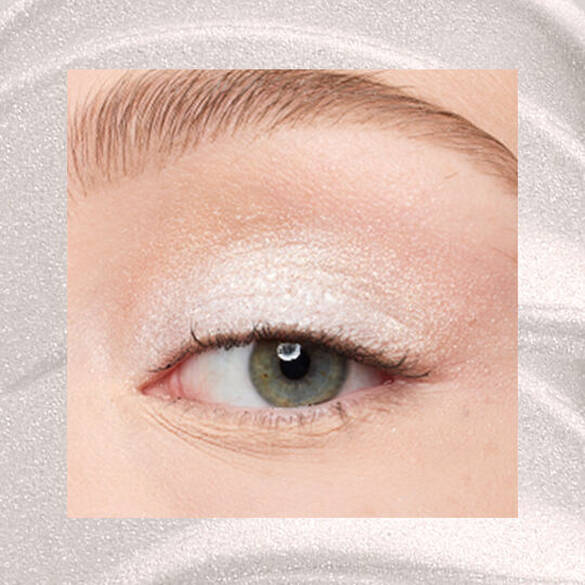 Close-up of an eye area with NYX Professional Makeup Lid Lingerie Cream Eye Pigment in 01 Satin Silver, shown on a shimmering silver textured background.